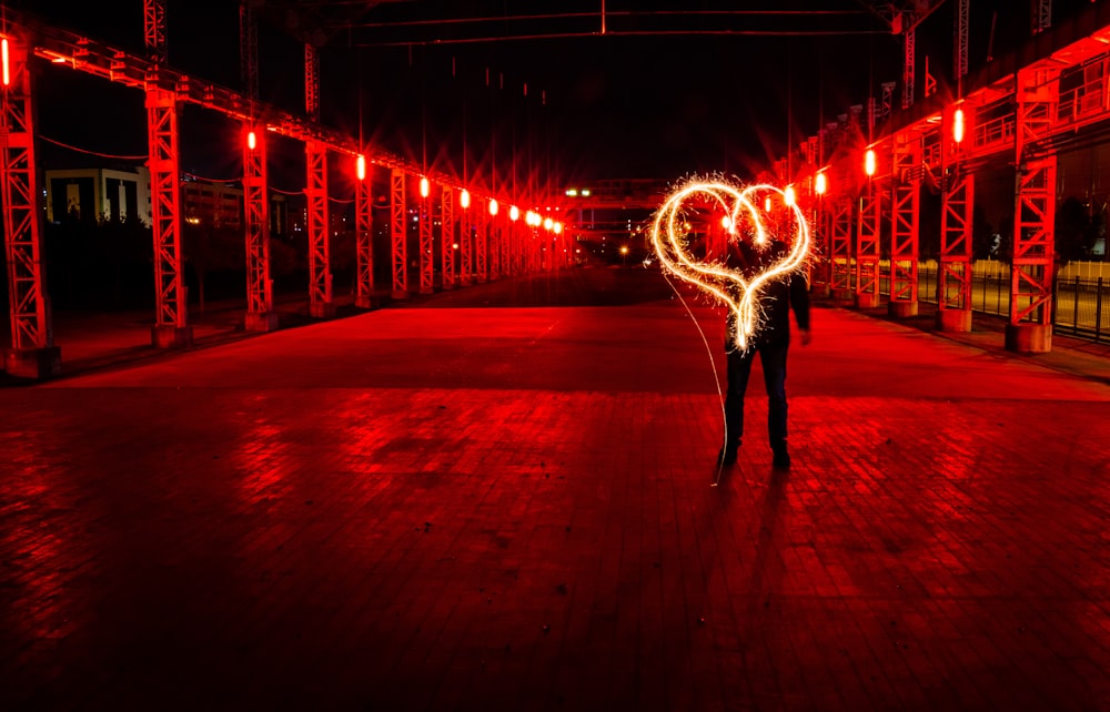 man standing behind heart light