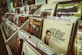 A collection of vinyl records is neatly arranged in a music store display. Various album covers are visible, featuring vintage designs and famous musicians like Glenn Miller, with organizer tabs labeling different artists.
