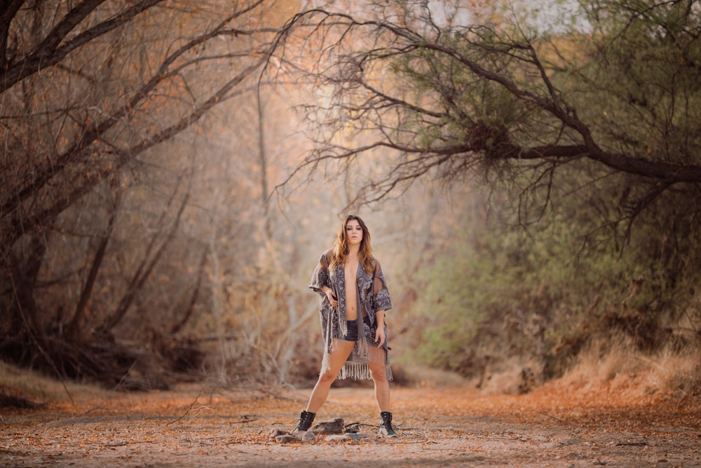 mulher em pé enquanto faz pose de modelagem sob árvore verde