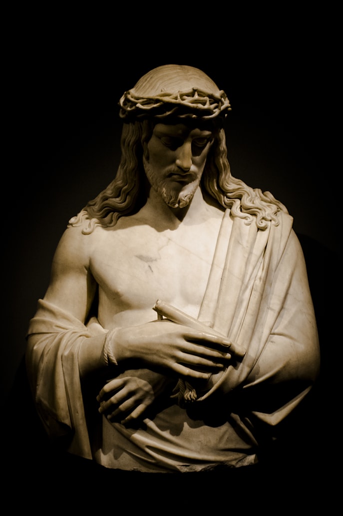 Marble bust of Jesus Christ, wearing a crown of thornes and looking downward solemnly. 