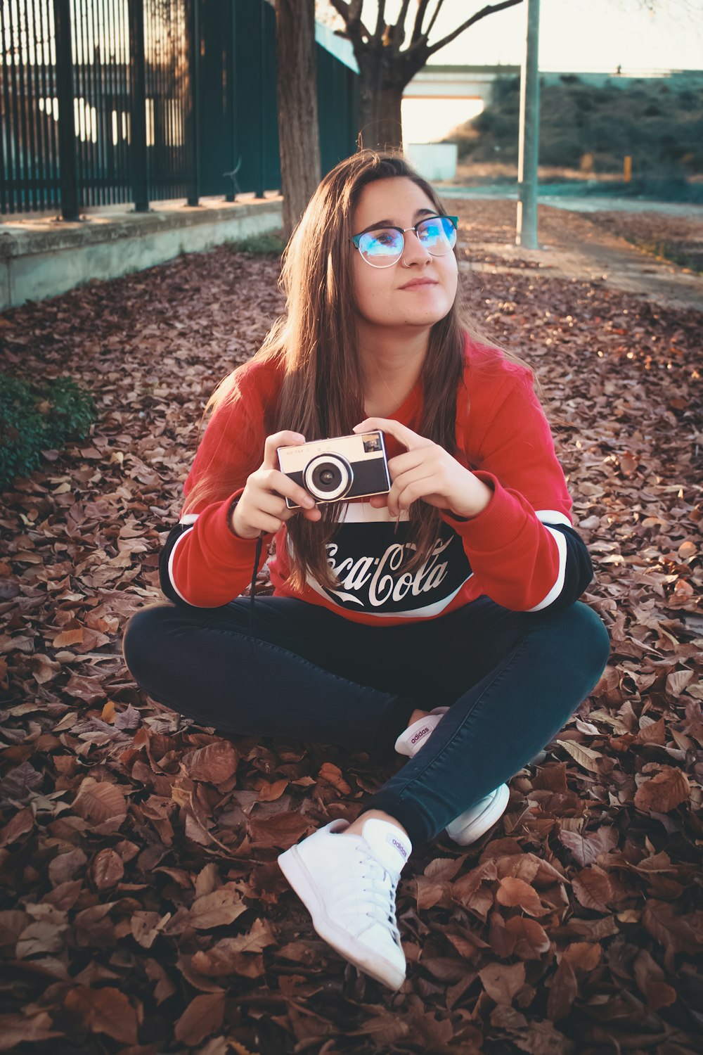 donna che indossa una camicia a maniche lunghe rossa e nera che tiene una fotocamera DSLR