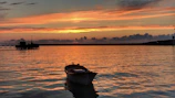 Golden sunset casting warm light over a wooden fishing boat anchored in the calm Po Delta lagoon