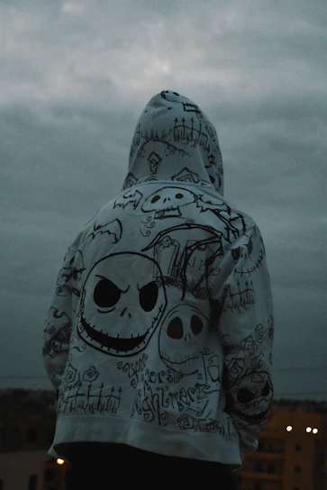 Dark hoodie featuring blood red and bone white sacred iconography over an aged wall with spray paint splatter