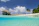 A cozy beachfront bungalow surrounded by tropical greenery under a clear blue sky.