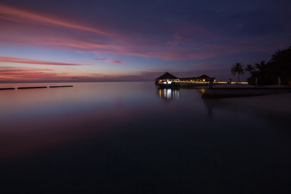 lighted gazebo across beach during pink sky sunset