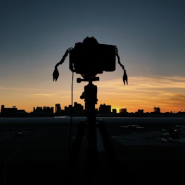 A behind-the-scenes shot of Shaun setting up a camera on a vibrant city rooftop at sunset.