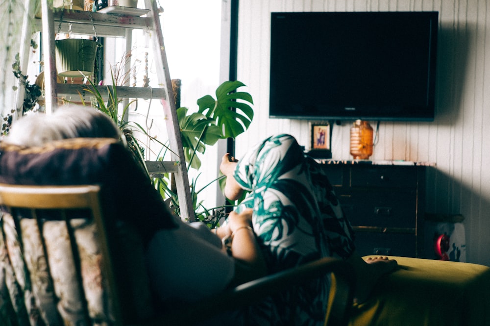 femme assise sur un fauteuil regardant la télévision éteinte