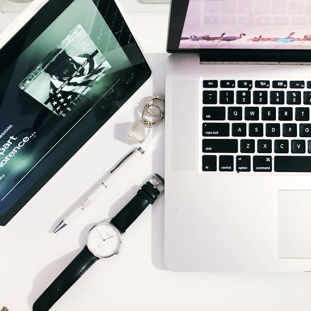 gray analog watch besides white pen