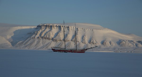 A schooner in front of a snow-covered mountain — Svalbard, Norway