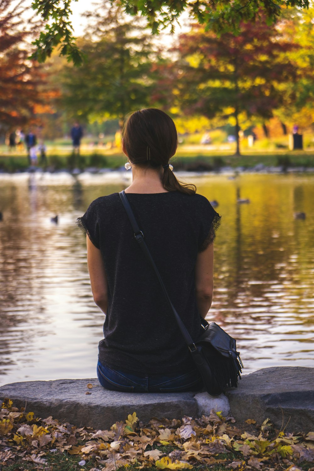 woman sitting on stone in front of lake