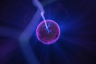 A luminous sphere emits vibrant purple and blue electric arcs within a glowing orb against a dark background.