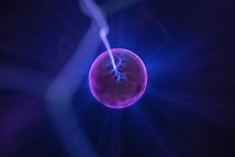 A luminous sphere emits vibrant purple and blue electric arcs within a glowing orb against a dark background.