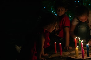 A family gathered around a table reading the Bible together with candles lit.