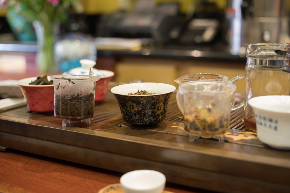 selective focus photo of cups and bowls on brown table