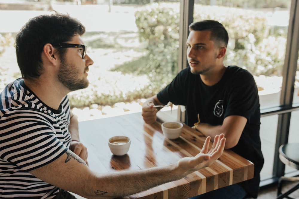 two men having conversation on table