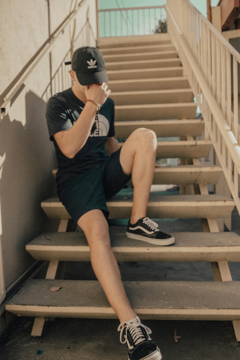 man sitting on stairs holding his face