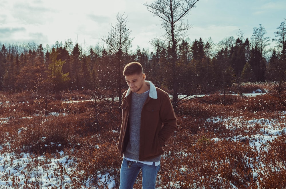 man wearing brown jacket standing on grass field