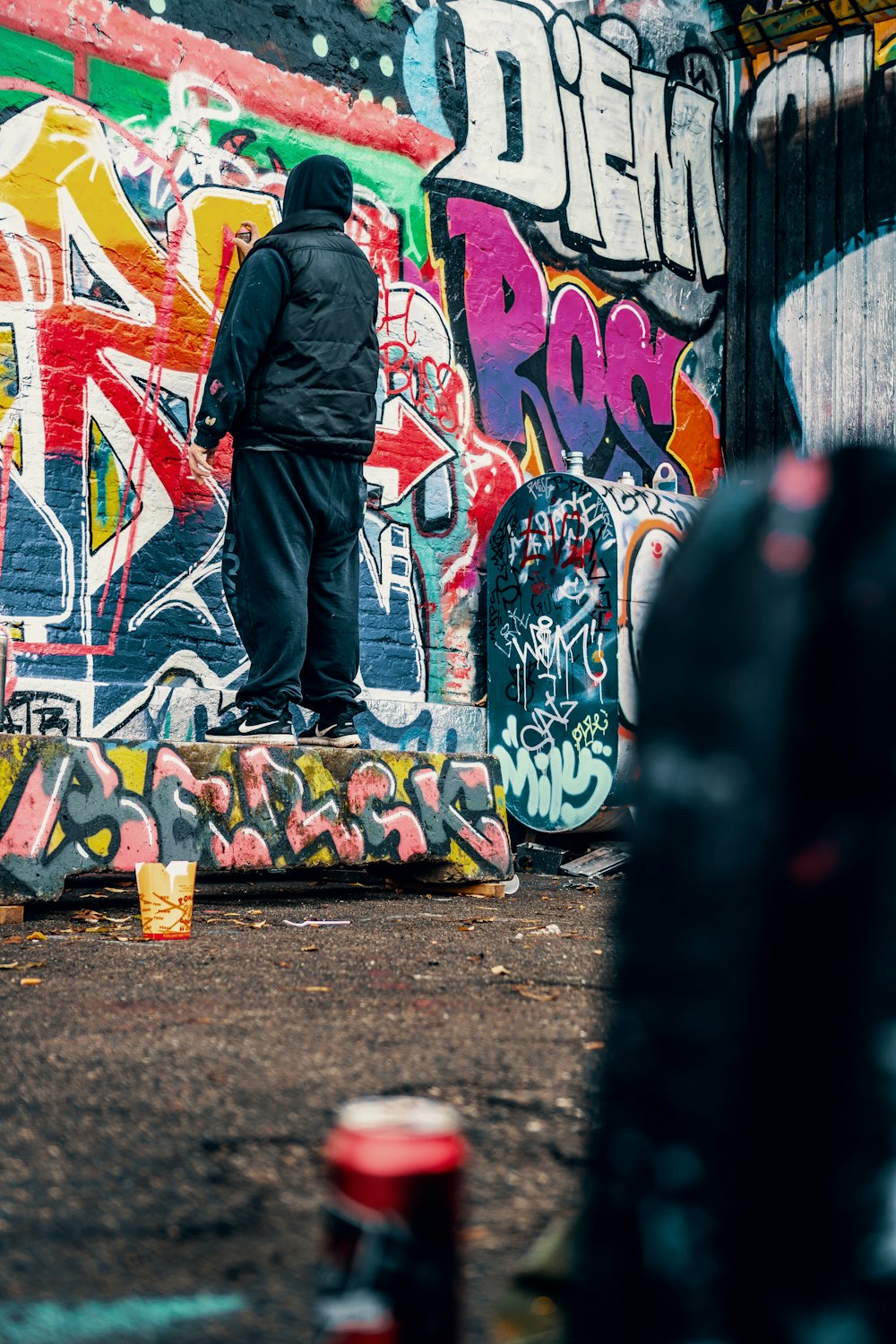 man standing on multicolored doodle art wall