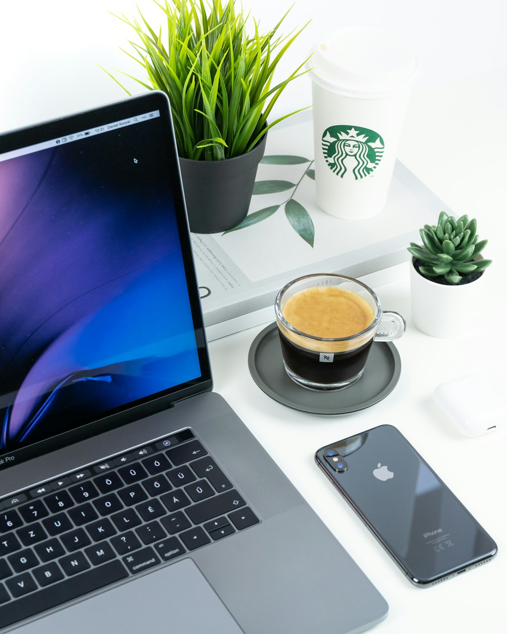 laptop beside iPhone and coffee in cup on table