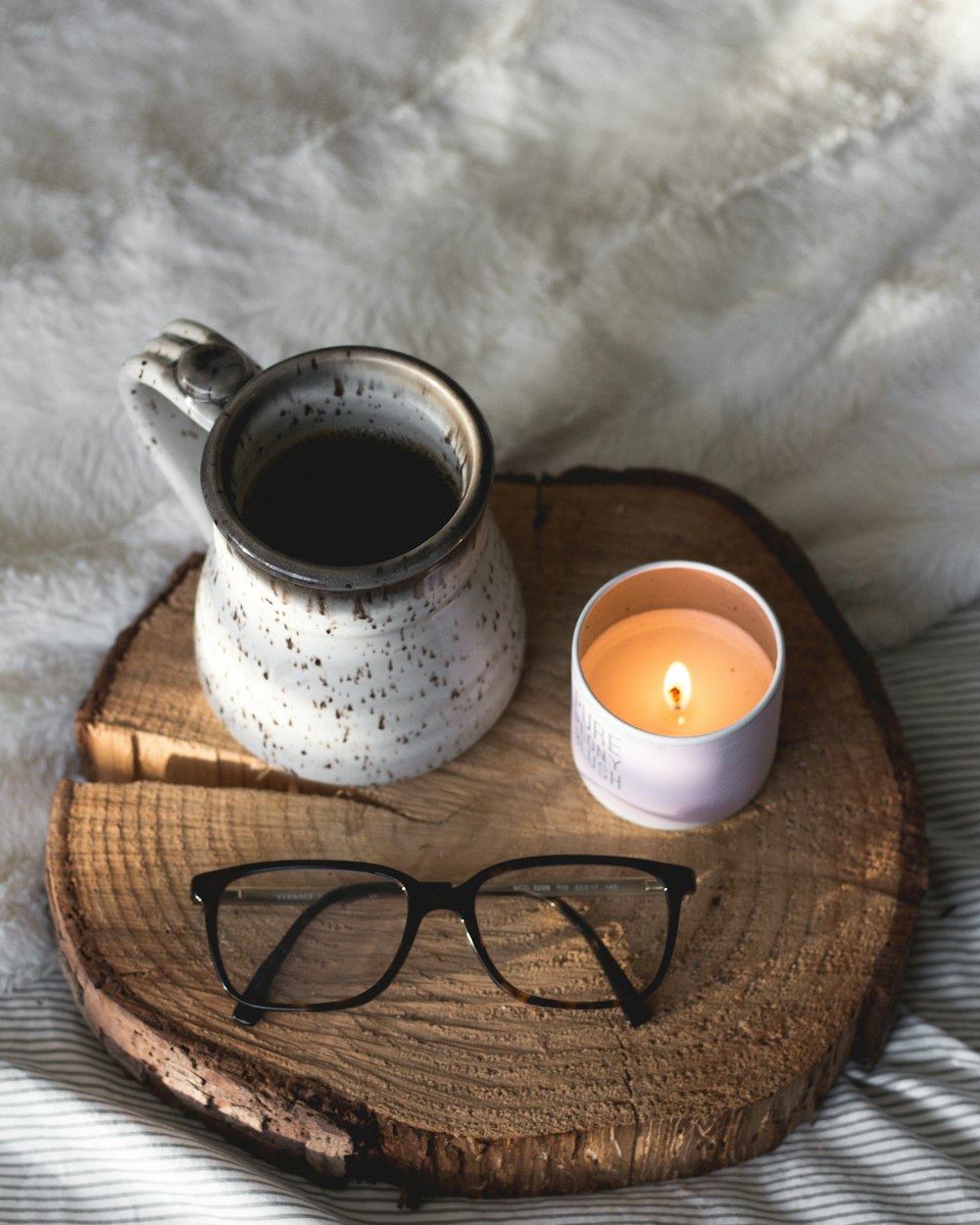 black-framed eyeglasses beside candle
