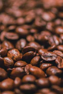 Close-up of roasted coffee beans with a warm, soft beige background.