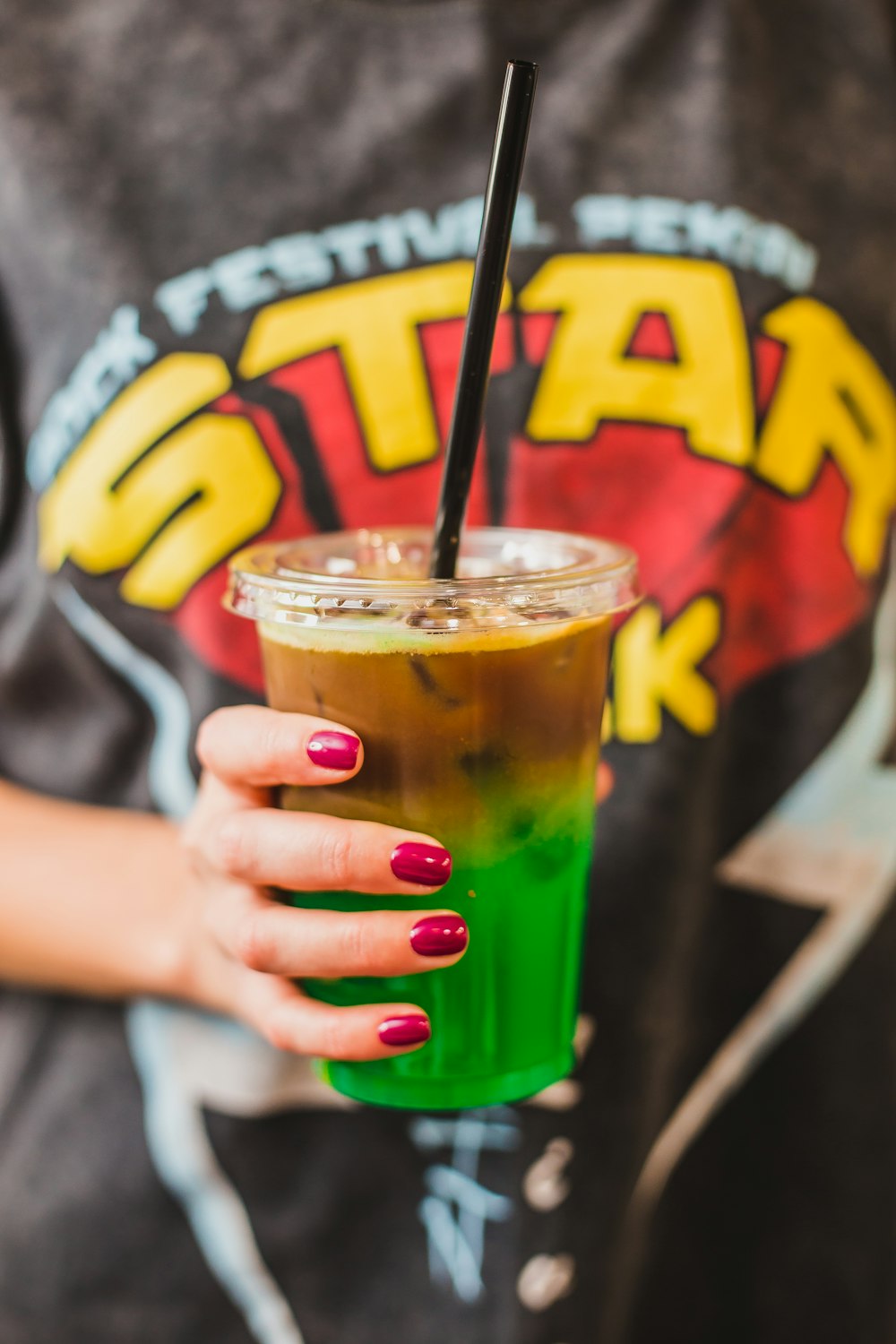 person holding clear plastic cup filled with green liquid