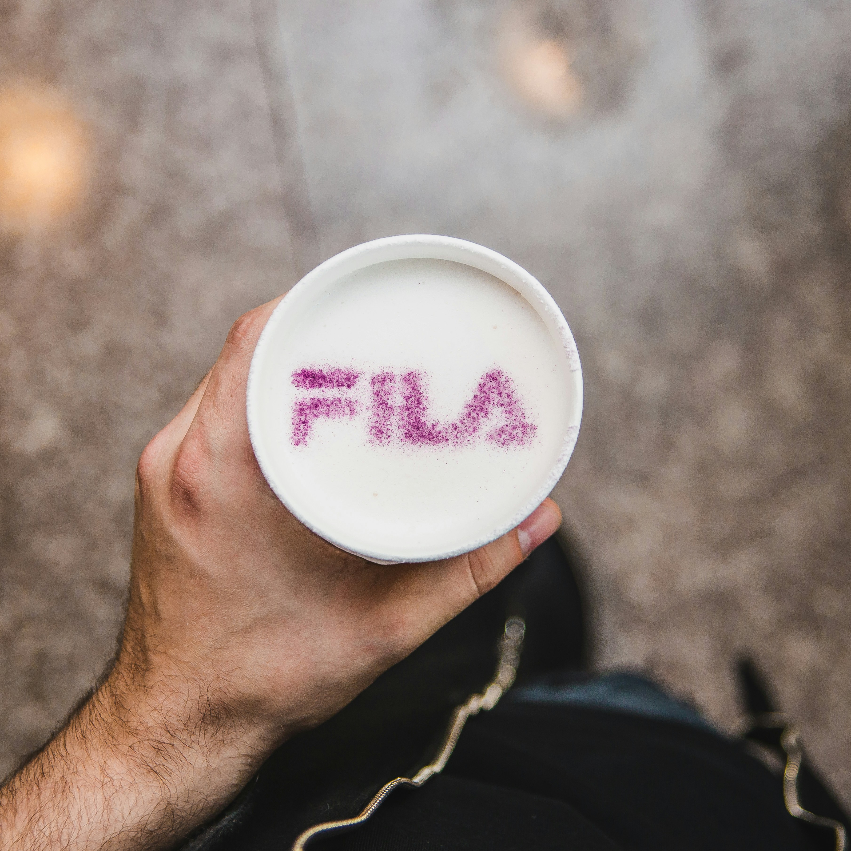 person holding cup with purple Fila text