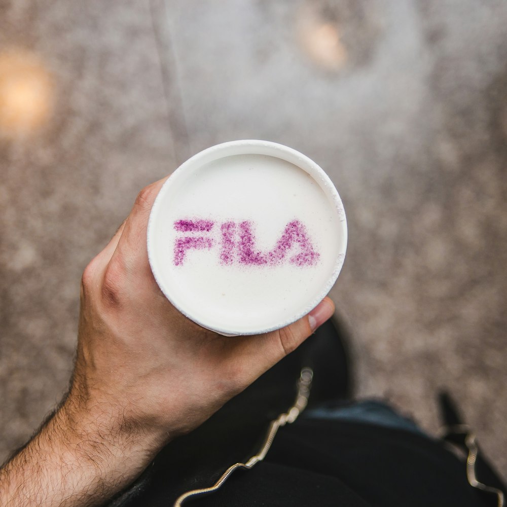 person holding cup with purple Fila text