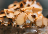 Close-up of a creamy tres leches cake with a caramel drizzle on a rustic wooden table.