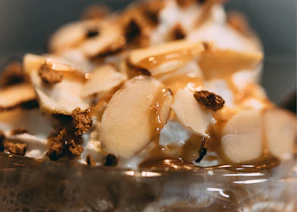 Close-up of a creamy tres leches cake with a caramel drizzle on a rustic wooden table.