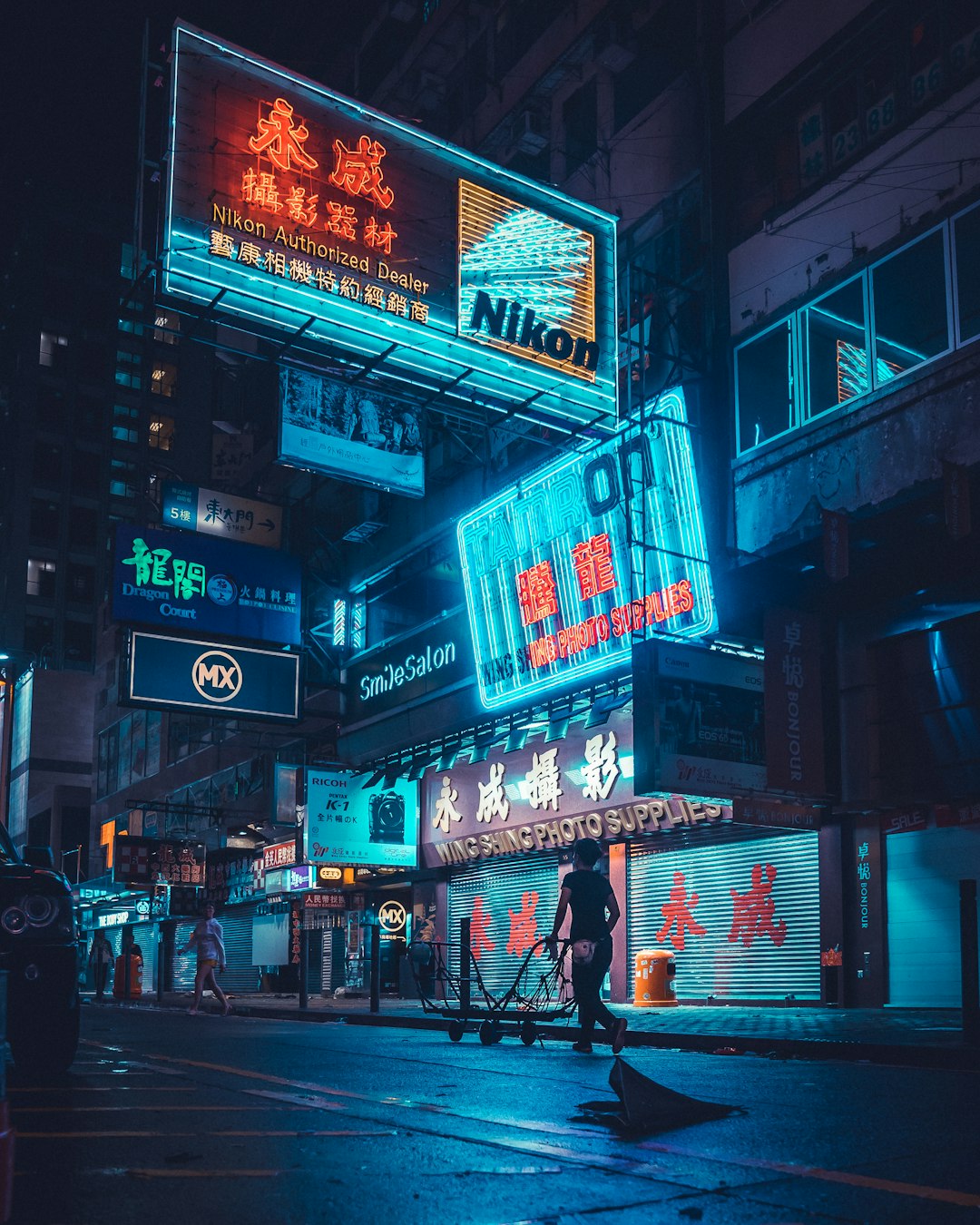 man pushing cart near building during nighttime