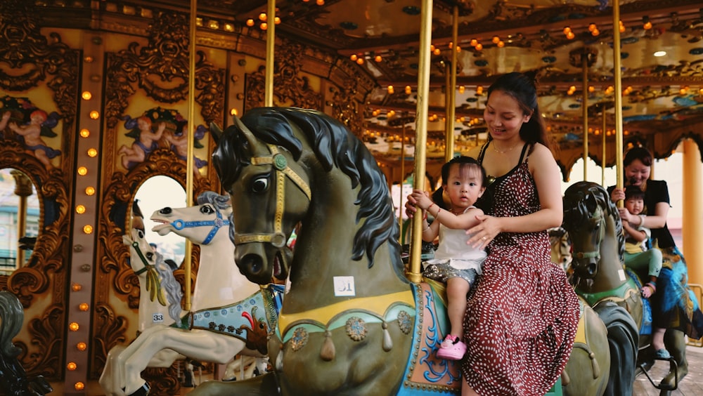 乗馬メリーゴーランドに乗った子供と女性