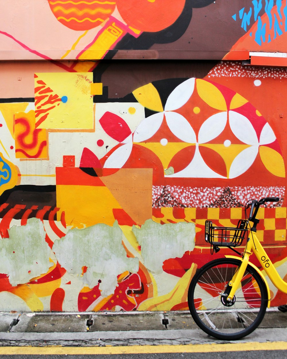 yellow city bike beside multicolored wall