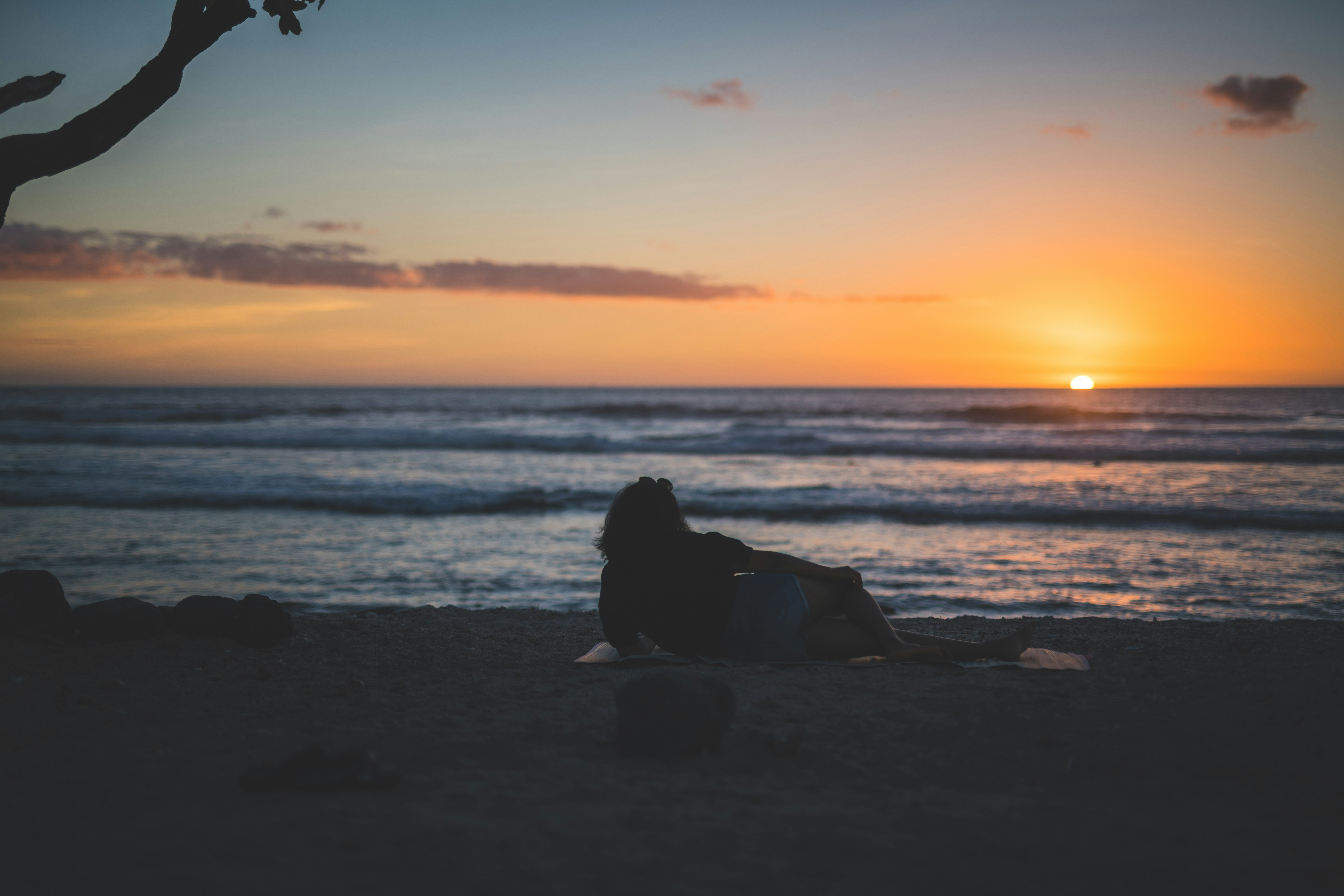 woman lying on shore during sunset