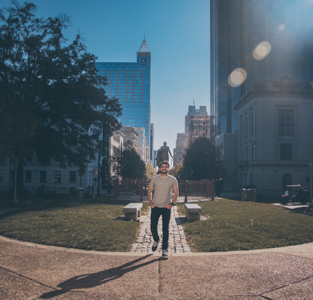 man wearing gray crew-neck shirt standing across gray statue