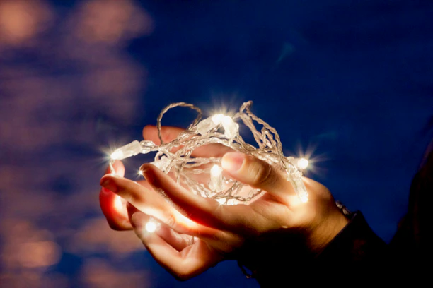 Close-up of hands holding a glowing product package with a soft-focus background of a cozy home setting.