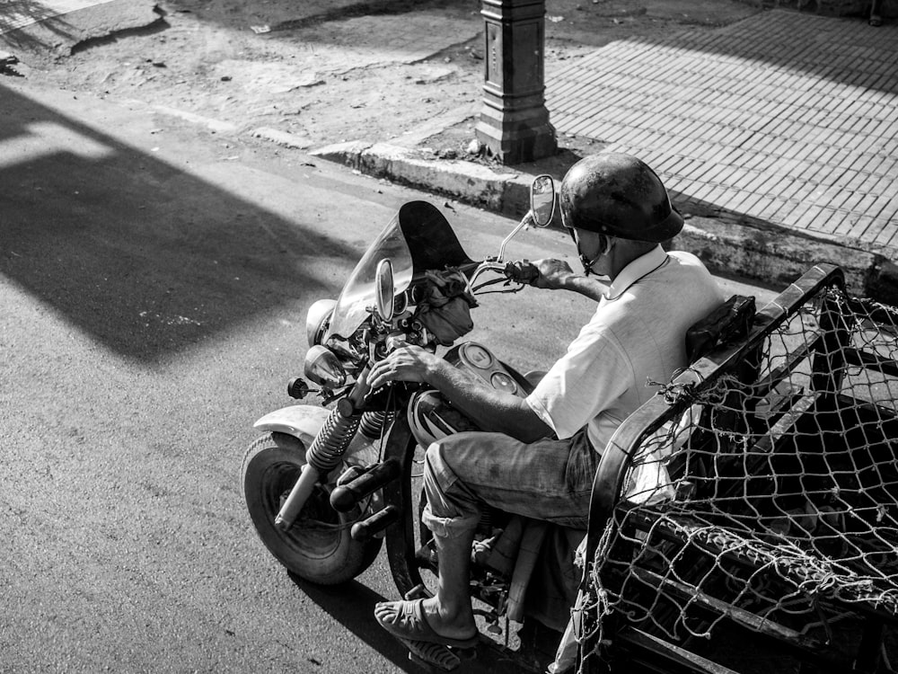 grayscale photo of man wearing white top riding motorcycle