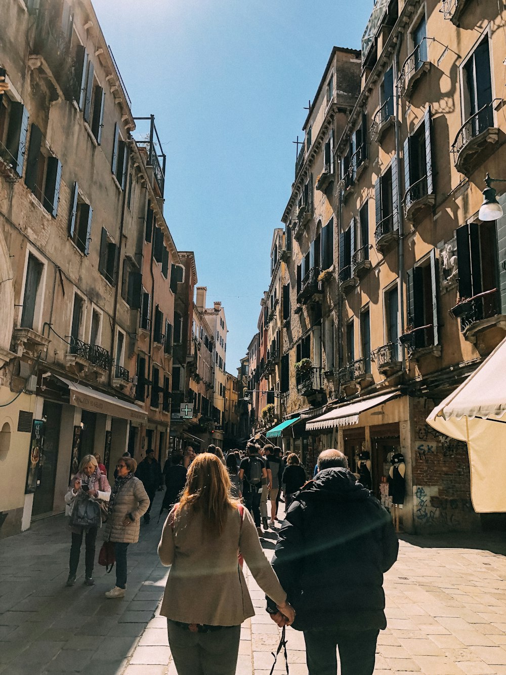 people in between buildings under blue sky during daytime