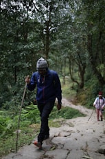 man holding stick walking in jungle during daytime