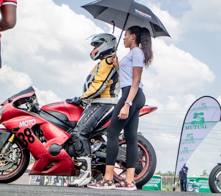A friendly agent assisting a motorcyclist with insurance paperwork at a sunny roadside cafe.