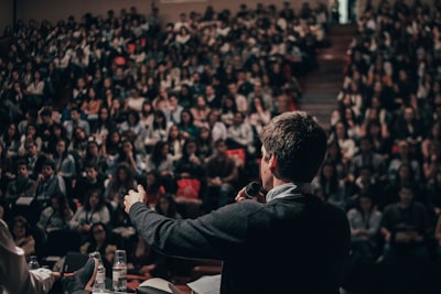 man speaking in front of crowd audience google meet background
