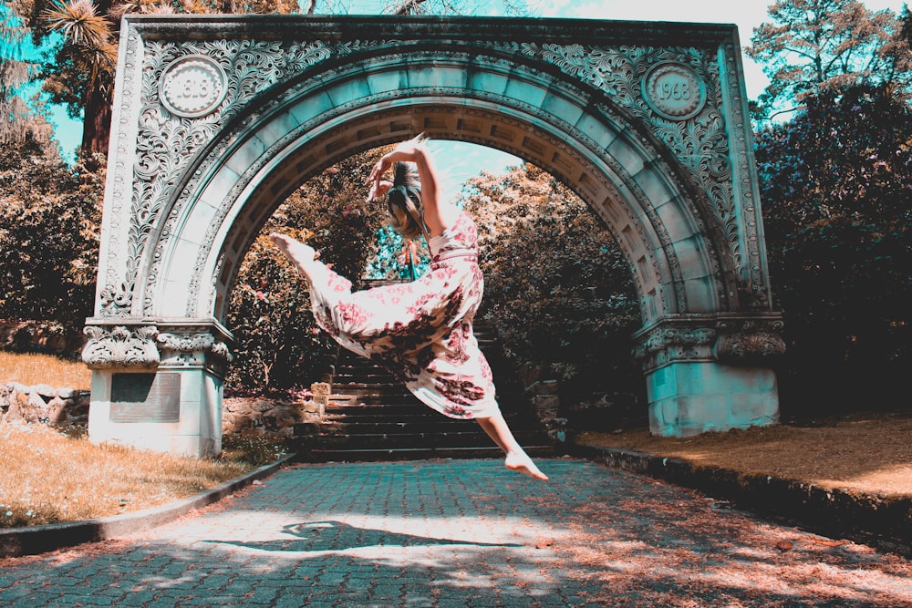 woman on mid air near arch gate during daytime