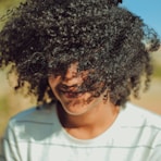 person wearing white crew-neck shirt with curly hair photo