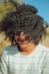 person wearing white crew-neck shirt with curly hair photo