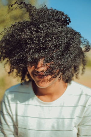 person wearing white crew-neck shirt with curly hair photo