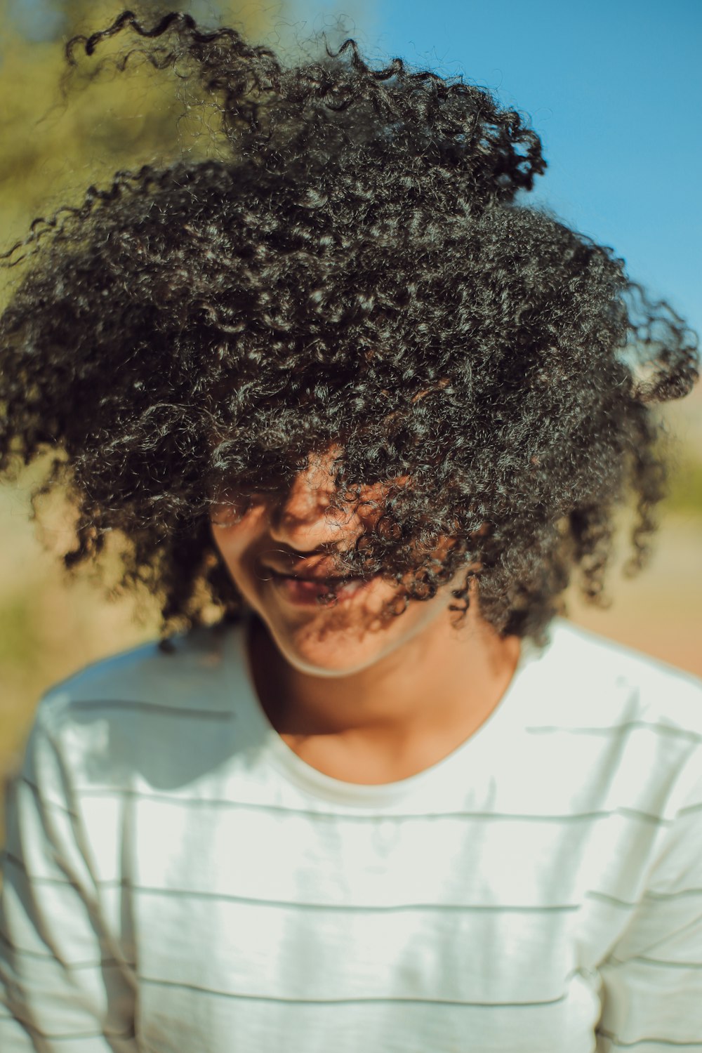 person wearing white crew-neck shirt with curly hair photo