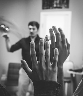 grayscale photography of two people raising their hands