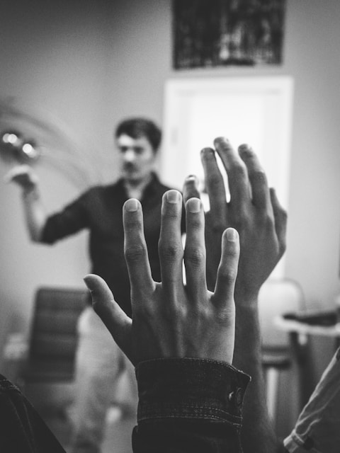 grayscale photography of two people raising their hands