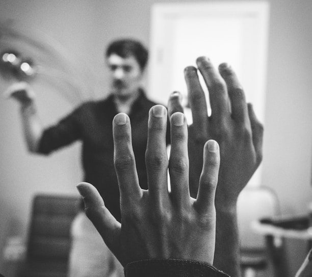 grayscale photography of two people raising their hands