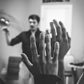 grayscale photography of two people raising their hands